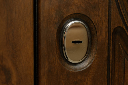 门是用木头包裹的。 木雕。 内部锁设计。 钥匙孔。 金属门把手。 防盗装甲门。 金属门。 门的设计。 窥视孔。