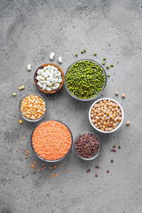各种五颜六色的豆类碗，扁豆，芸豆，鹰嘴豆，绿豆，灰色背景，顶部视图复制空间。 健康食品节食营养概念纯素蛋白来源。