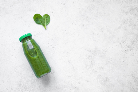 绿色冰沙瓶与心形菠菜在白色背景顶部视图。 排毒清洁饮食和健康饮食概念复制空间。