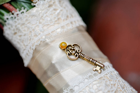 婚礼花束的花束腿，装饰着一条白色丝带和一把小的老式钥匙。