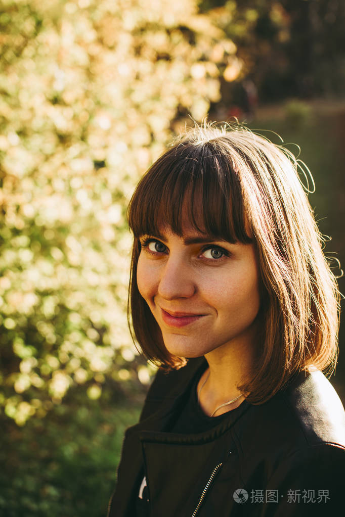 快乐的白种人女孩反对秋天的灌木丛在植物园. 漂亮的蓝眼睛.