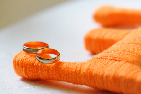 装饰橙色字母e上的金色结婚戒指。