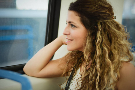 坐在窗边坐火车旅行的年轻漂亮的女人。 享受旅行的概念。