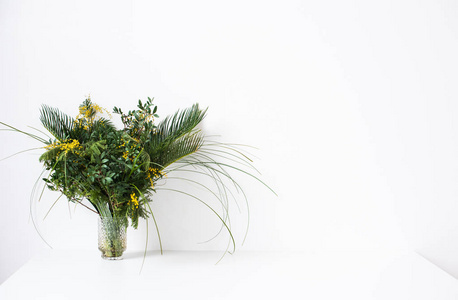 简单的花束与绿叶和含羞草花和空白色的墙壁