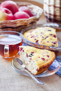 杯盘上的一块牛莓派，背景上的一杯茶和一篮子苹果
