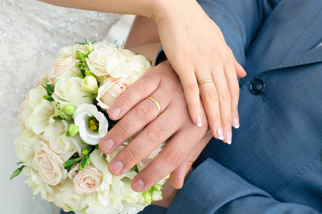 新婚夫妇的手在新娘的花束上戴着结婚戒指。