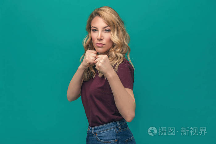 美丽的年轻女子在拳击手站立摆姿势在蓝色背景