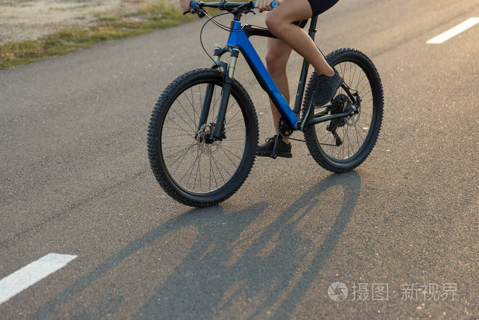 女孩骑着山地车在越野上,美丽的肖像自行车在日落健身