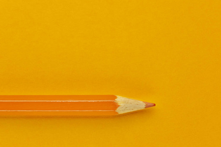 橙色背景上的一支橙色铅笔，美丽的单色效果