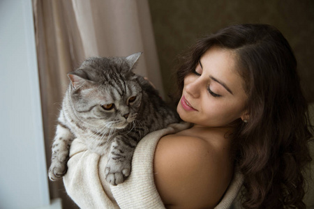 美丽的女孩抱着一只灰色的大猫