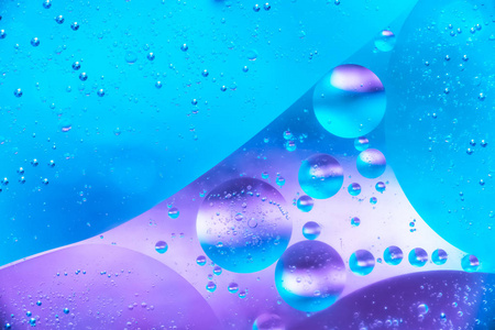 水和油泡蓝色背景。 宏观拍摄美丽的水和油泡背景与小和大泡泡。