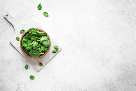 婴儿菠菜叶子放在碗里，白色背景，顶部视图，复制空间。清洁饮食，排毒，饮食食物成分绿色有机菠菜。