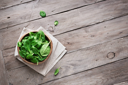 绿色婴儿菠菜叶在碗中的木制背景顶部视图复制空间。 清洁饮食排毒饮食成分绿色有机菠菜。