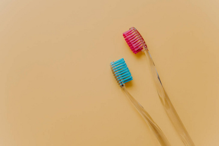 两个蓝色和红色塑料牙刷隔离在黄色背景上，空的空间为您的推广。 孤立的物体