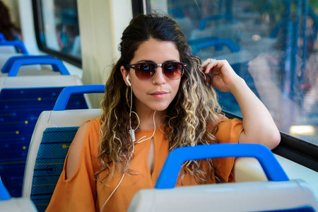 坐在窗边坐火车旅行的年轻漂亮的女人。 享受旅行的概念。