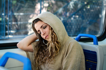 睡在火车上的年轻城市妇女在窗边旅行。 现代人的城市生活方式。