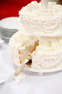 一个漂亮的白色两层婚礼蛋糕和一个切块。