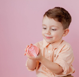 带着礼物的快乐小男孩。 照片隔离在粉红色背景上。 微笑的男孩拿着礼物盒。 假期和生日的概念。