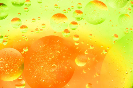 水和油泡黄色橙色背景。 宏观拍摄美丽的水和油泡背景与小和大泡泡。