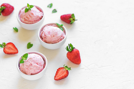 白色背景顶部的草莓冰淇淋和新鲜草莓。 三碗草莓冰淇淋健康夏季甜点。