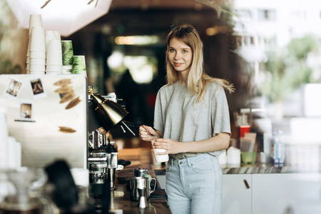 一个年轻可爱的瘦金发碧眼, 穿着休闲装, 正在一家现代化的咖啡店煮咖啡。咖啡的制作过程如下