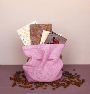 巧克力酒吧在粉红色的袋子上紫色的背景和咖啡豆。巧克力。巧克力
