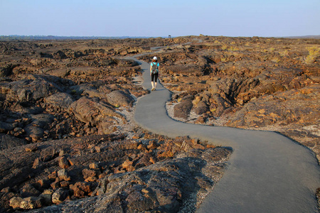 女人走在小径上，来到美国爱达荷州月亮国家纪念碑的洞穴区陨石坑。