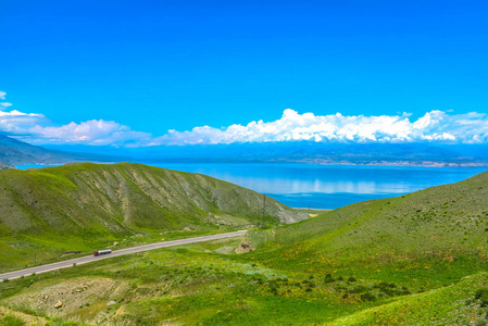 托克托古尔水库湖泊景观与雪盖苏萨米尔太山脉，卡车公路。