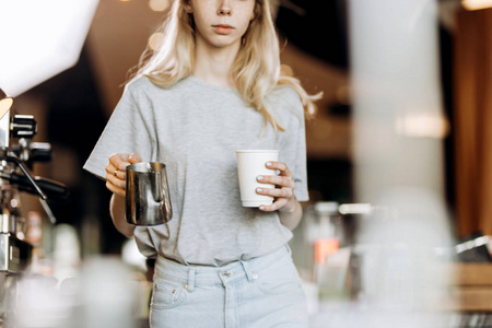 一个长头发的漂亮的苗条金发女郎, 穿着休闲装, 正在一家现代化的咖啡店煮咖啡。咖啡的制作过程如下