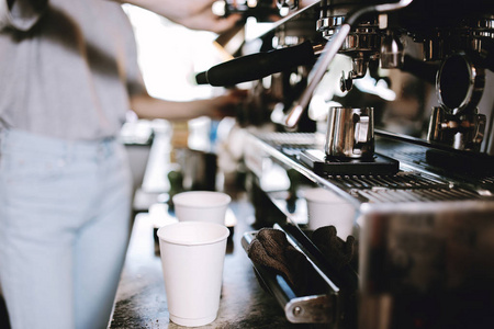 烹饪咖啡的过程是展示的。两个杯子站在咖啡机旁边, 而咖啡店则在一家舒适的咖啡店里准备
