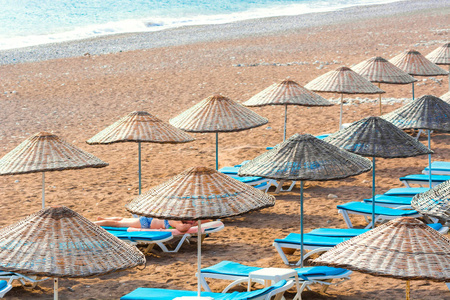 躺椅在Cirali海滩上的草伞下。 地中海海岸土耳其莱西亚。