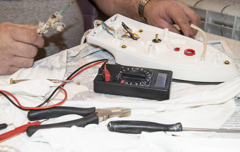 特写镜头的老电工手, 使用数字电压表来修复电熨斗, 选择性聚焦