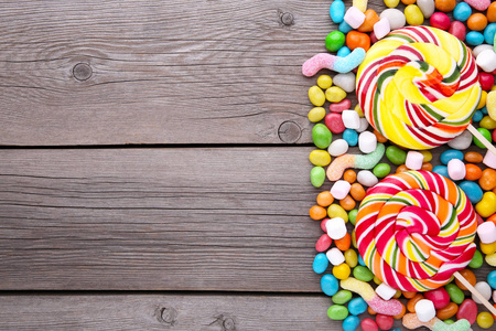 彩色棒棒糖，灰色木制背景的彩色圆形糖果