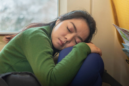 美丽的亚洲女人通过休息和睡在火车上为旅行做好准备。