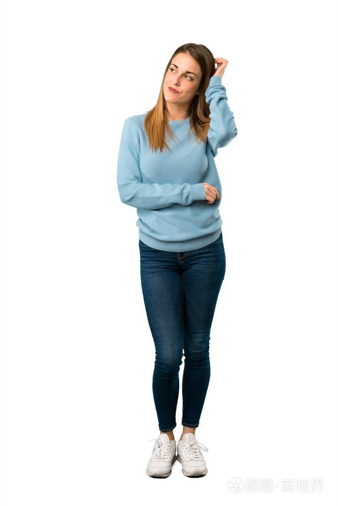 全身的金发女人穿着蓝色衬衫在白色背景上挠头时有疑问