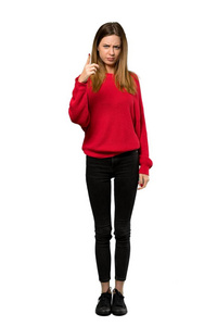 一个穿着红色毛衣的年轻女子的完整镜头，沮丧地指着前面的孤立的白色背景