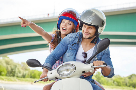 在阳光明媚的日子里，一对快乐的年轻夫妇在着摩托车