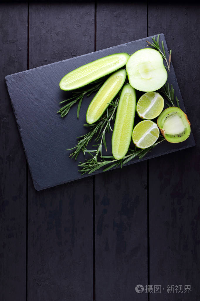 绿色水果,蔬菜和迷迭香在黑色背景和复制空间.