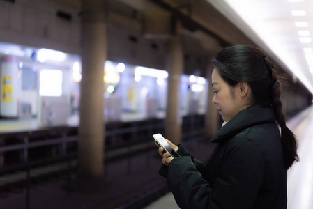 接近快乐的亚洲女人等待火车去日本东京火车站工作.照片