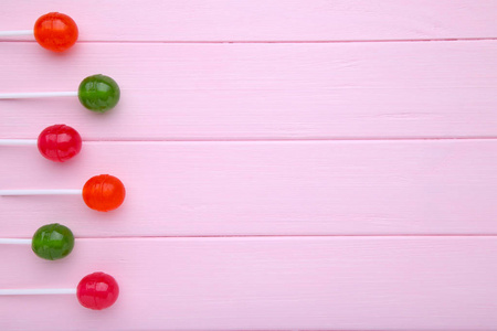 粉红色木制背景上的红色和绿色棒棒糖。 甜糖概念