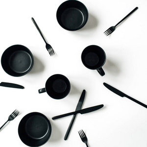 黑色时尚厨具叉子在白色背景上编织杯子碗。 平躺式俯视现代厨房概念。