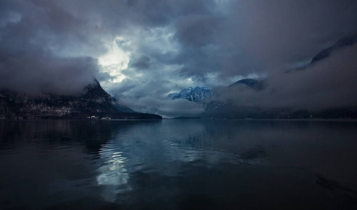 傍晚群山中的冬湖上的超现实画面，黑暗的天空和亮点