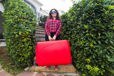 假日旅行和旅游概念带着沉重的红色手提箱的惊讶的年轻女子