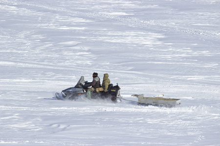 渔民雪上摩托骑在冰冻的河流上。
