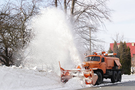 一辆有犁的大汽车从雪中清除了道路。 橙色货物专用设备在冬天与元素搏斗。 消除暴风雪的影响。 交通困难冻水。