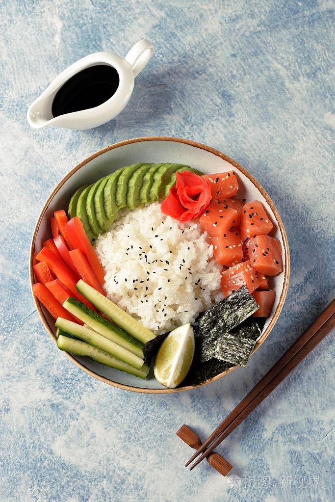 寿司碗,米饭三文鱼,鳄梨,黄瓜,甜椒,生姜和芝麻. 健康的食物.