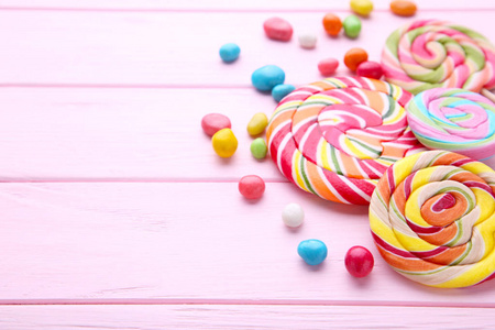 五颜六色的棒棒糖和粉红色背景上不同颜色的圆形糖果