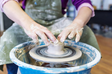 s wheel. Hands sculpts a cup from clay pot. Hands closeup