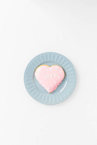 心形饼干与爱标志在蓝色盘子白色纹理背景。 情人节简约概念文本复制空间