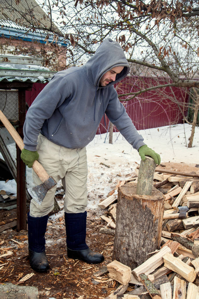 伐木工人在寒冷季节的房子里为炉子砍柴